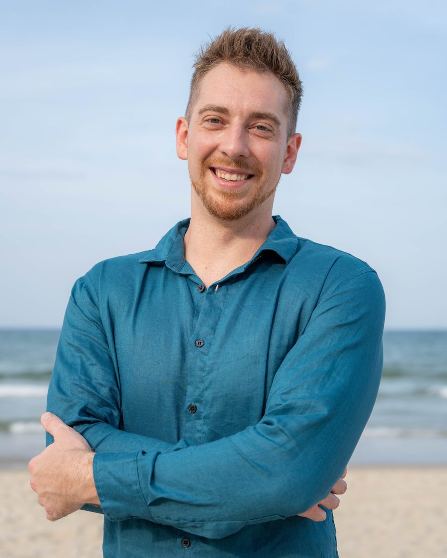 Tanner Niels, smiling, arms crossed, on a beach
